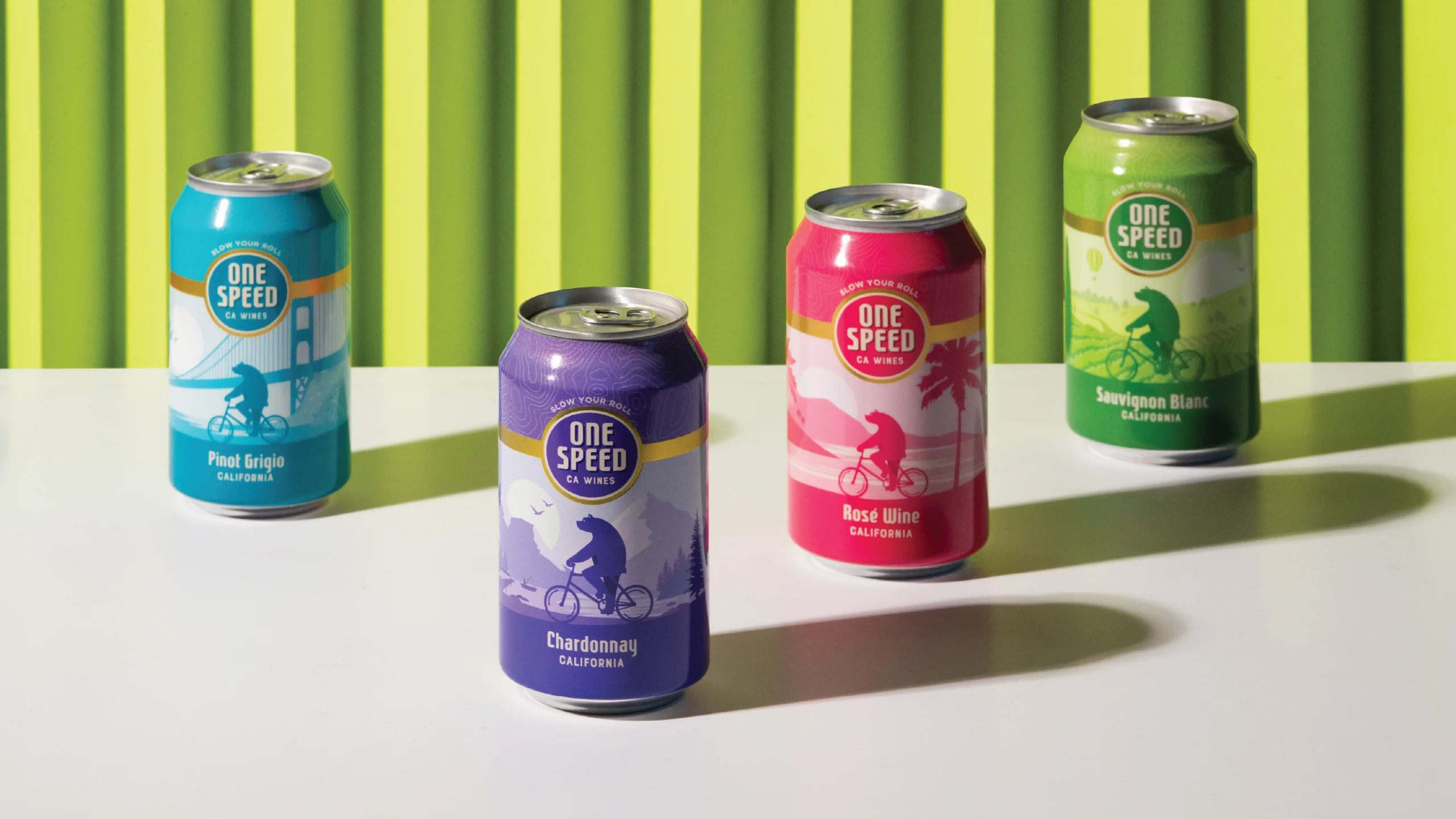 Four colorful One Speed wine cans with a bear riding a bicycle through California landscapes