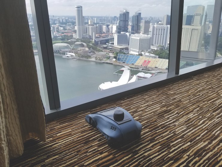 An early Rosie commercial cleaning robot operating on carpet beside a hotel window