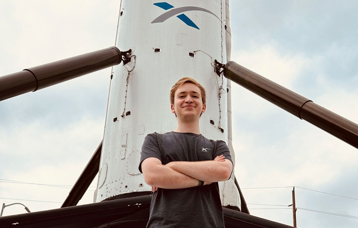 Michael Baron standing in front of a SpaceX rocket during his 2023 internship