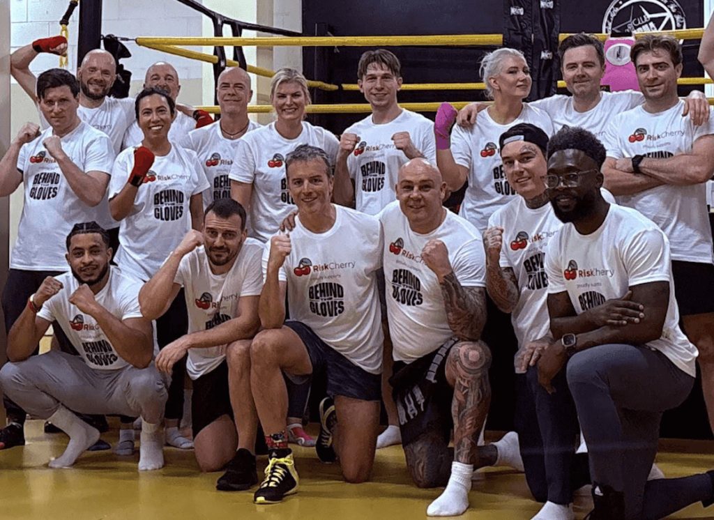 Behind The Gloves participants posing together in a boxing gym