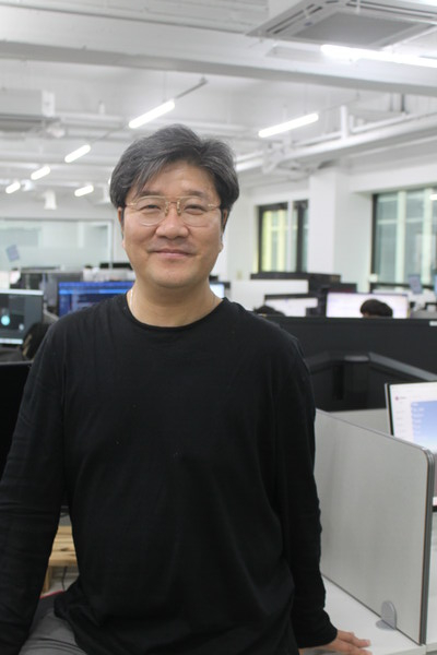 Michael Chong in a black sweater standing beside desks and monitors at Seerslab