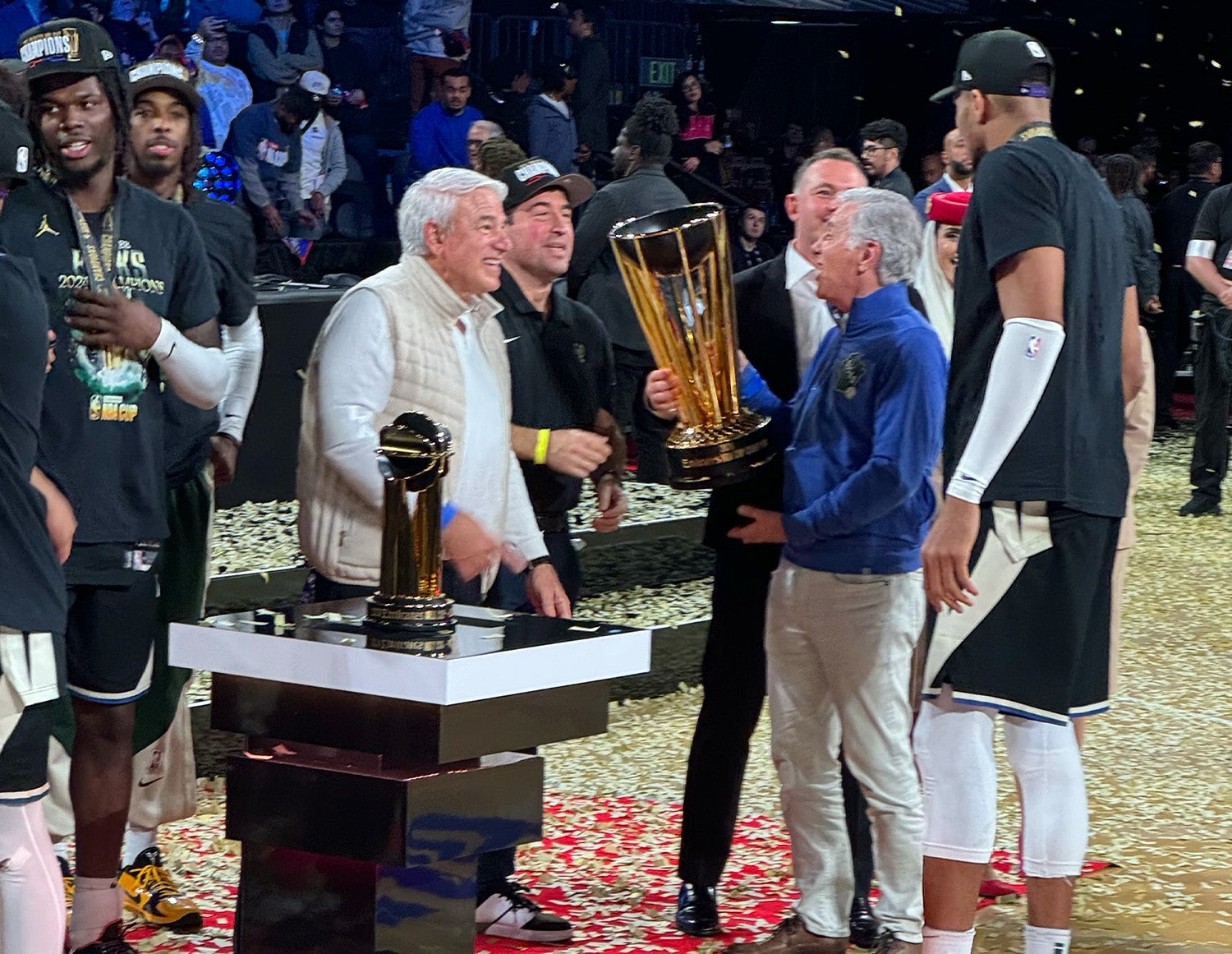 Michael Fascitelli in a blue top, holding the NBA Cup trophy during the Milwaukee Bucks celebration