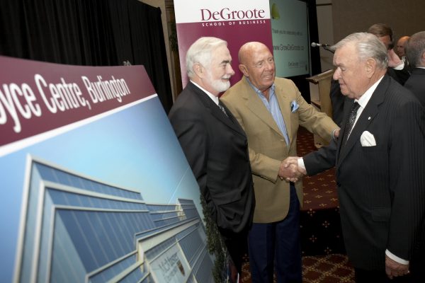 Michael G. DeGroote, centre, with McMaster leadership beside a Ron Joyce Centre display in 2009