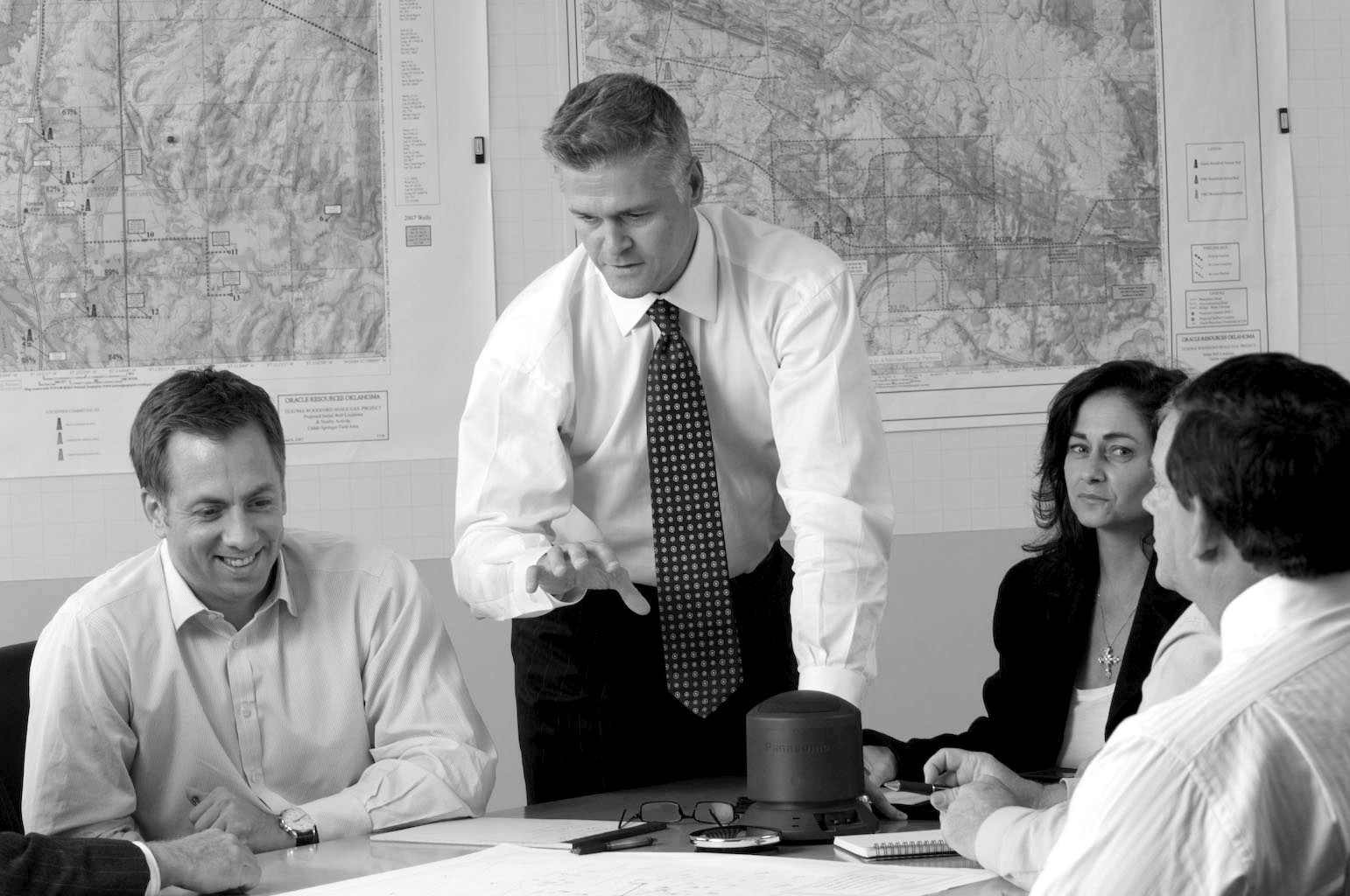 Michael Greer standing at a table with three colleagues, with maps on the wall behind them