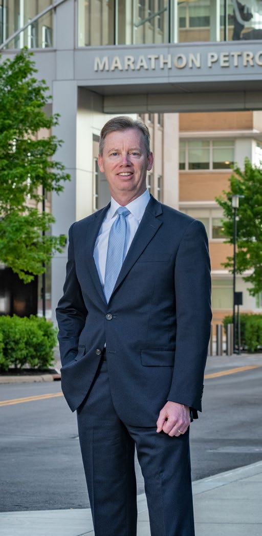 Michael Hennigan standing outside a Marathon Petroleum building in a dark suit and blue tie