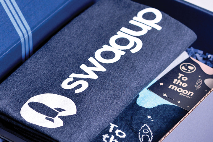 A SwagUp box containing a folded branded shirt and patterned socks