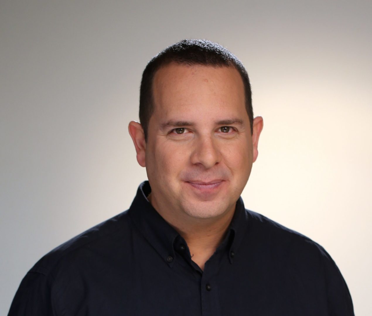 Michael Melnick in a dark shirt against a neutral studio background