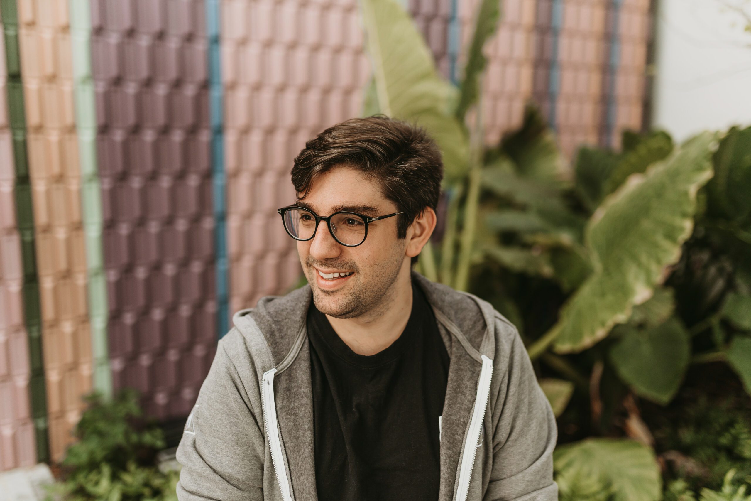 Michael Rangel seated in a gray hoodie, with green plants behind him