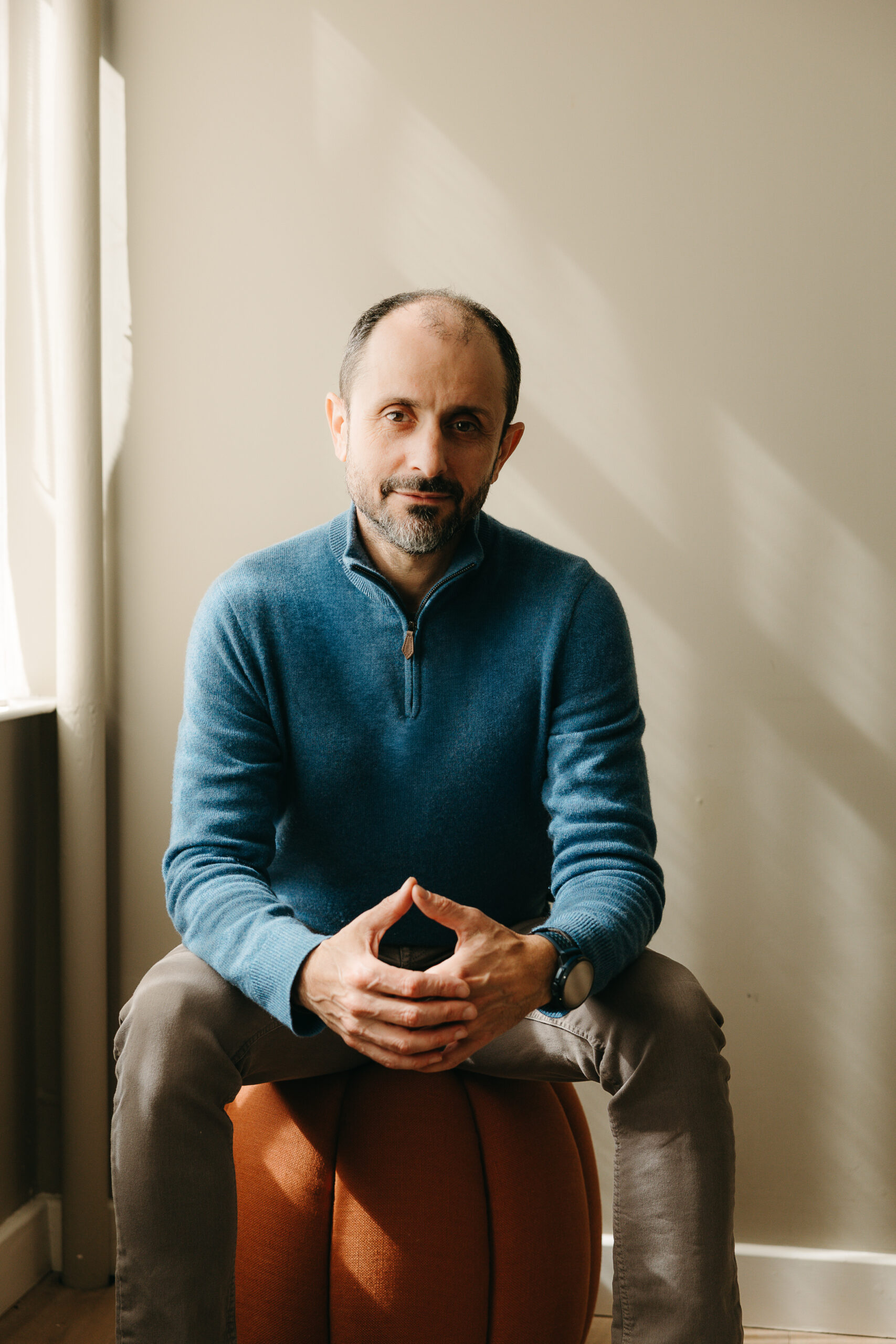 Michael Schreibmann seated beside a window, wearing a blue sweater