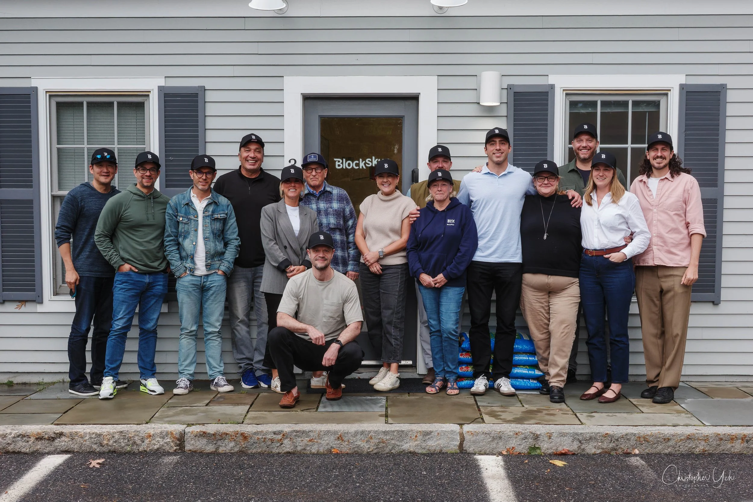 Blockskye colleagues gathered outside their Massachusetts office, including Michael Share in a blue plaid shirt near the center.