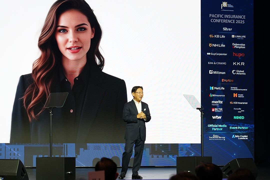 Michael Shin standing on the PIC 2025 stage beside the onscreen AI adviser Jenny