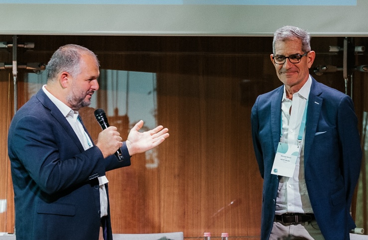 Michael Simon, at right, alongside a speaker holding a microphone at his 2025 Harsányi Prize recognition.