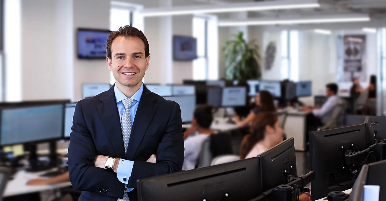 Michael Talve standing among desks and computer monitors at Expert Institute