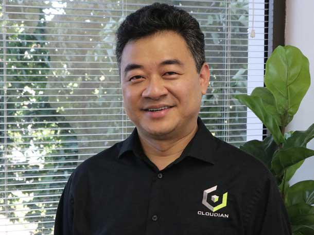 Michael Tso wearing a black Cloudian shirt in an office beside a window and a plant