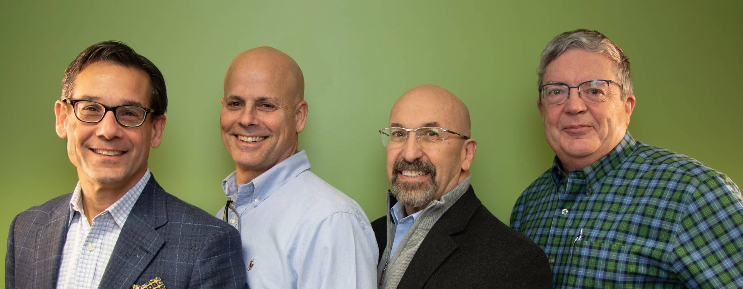 ConnectPay executive team standing together against a green wall
