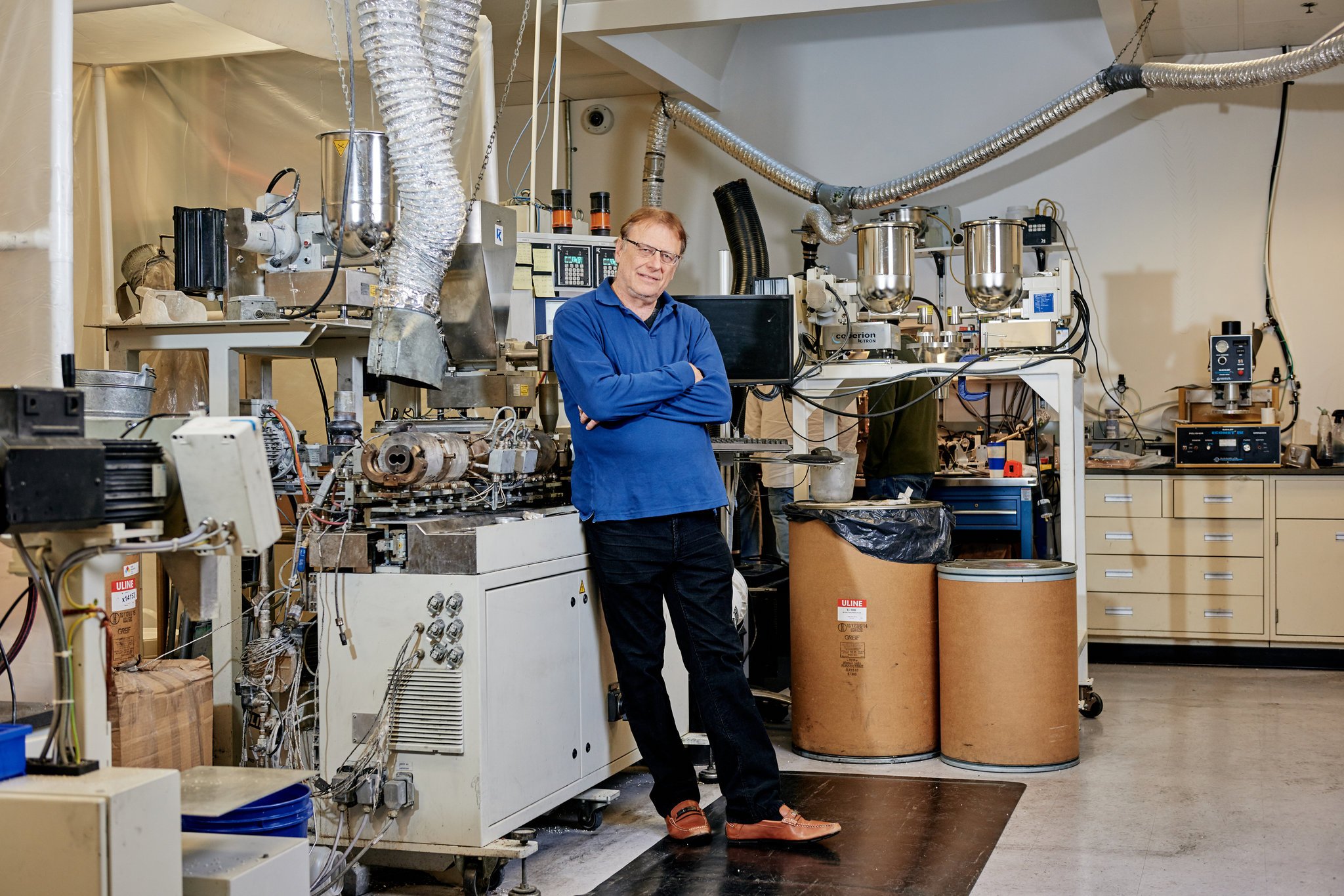 Michael Zimmerman standing among polymer processing equipment in a laboratory