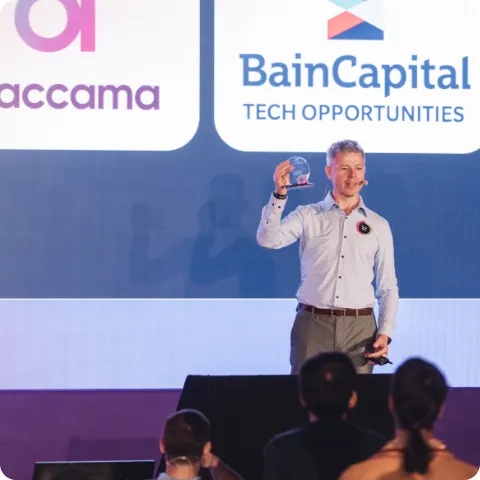 Michal Klaus raises a glass on stage in front of Ataccama and Bain Capital Tech Opportunities branding at the 2022 Allstaff event.