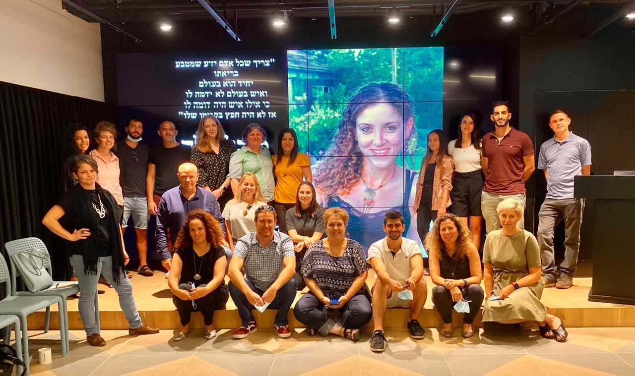 Members of the first Michal Sela Startup Academy cohort gathered in front of a portrait of Michal Sela