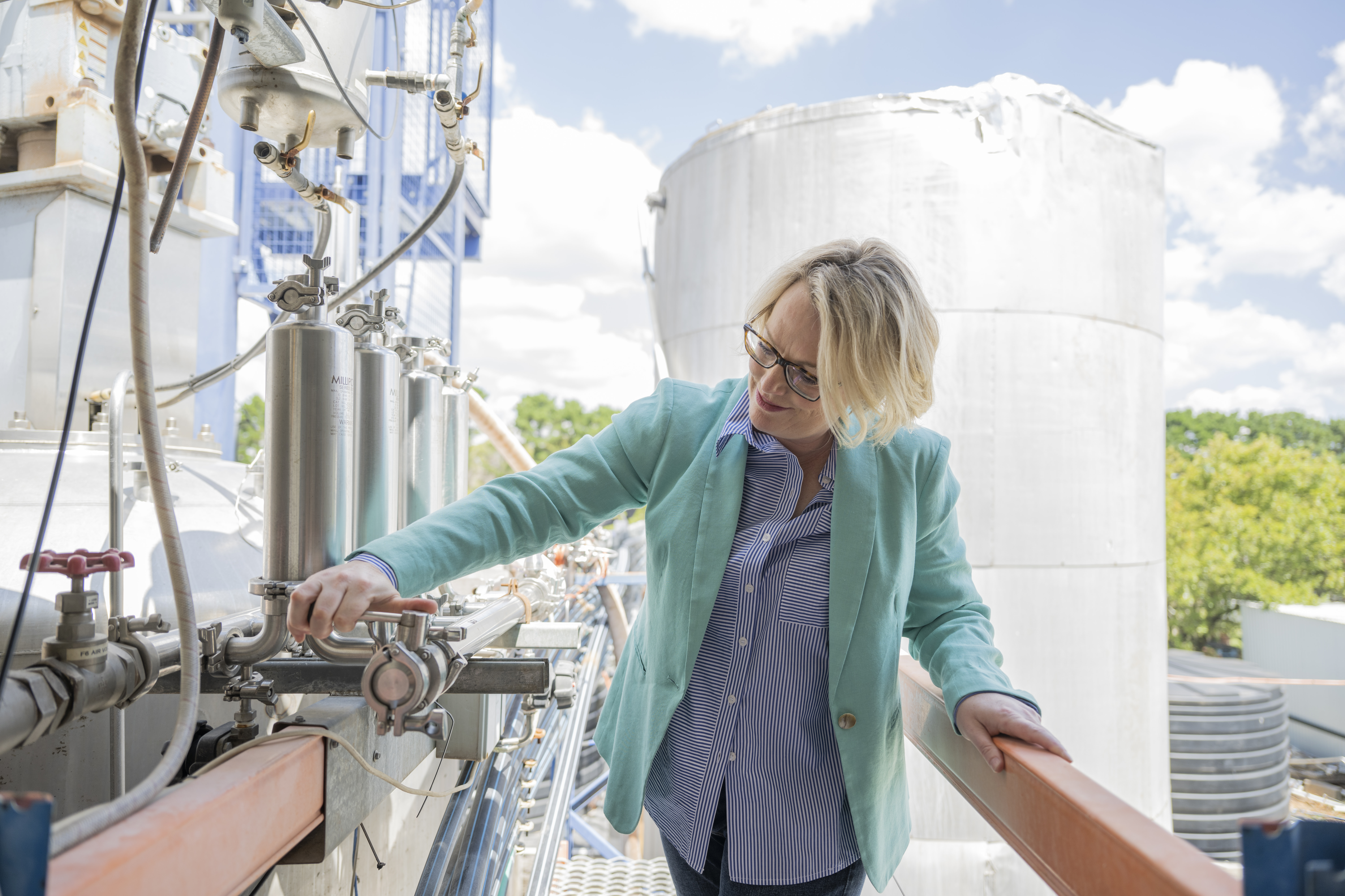 Michele Stansfield examining pipework beside fermentation equipment at the Orange facility