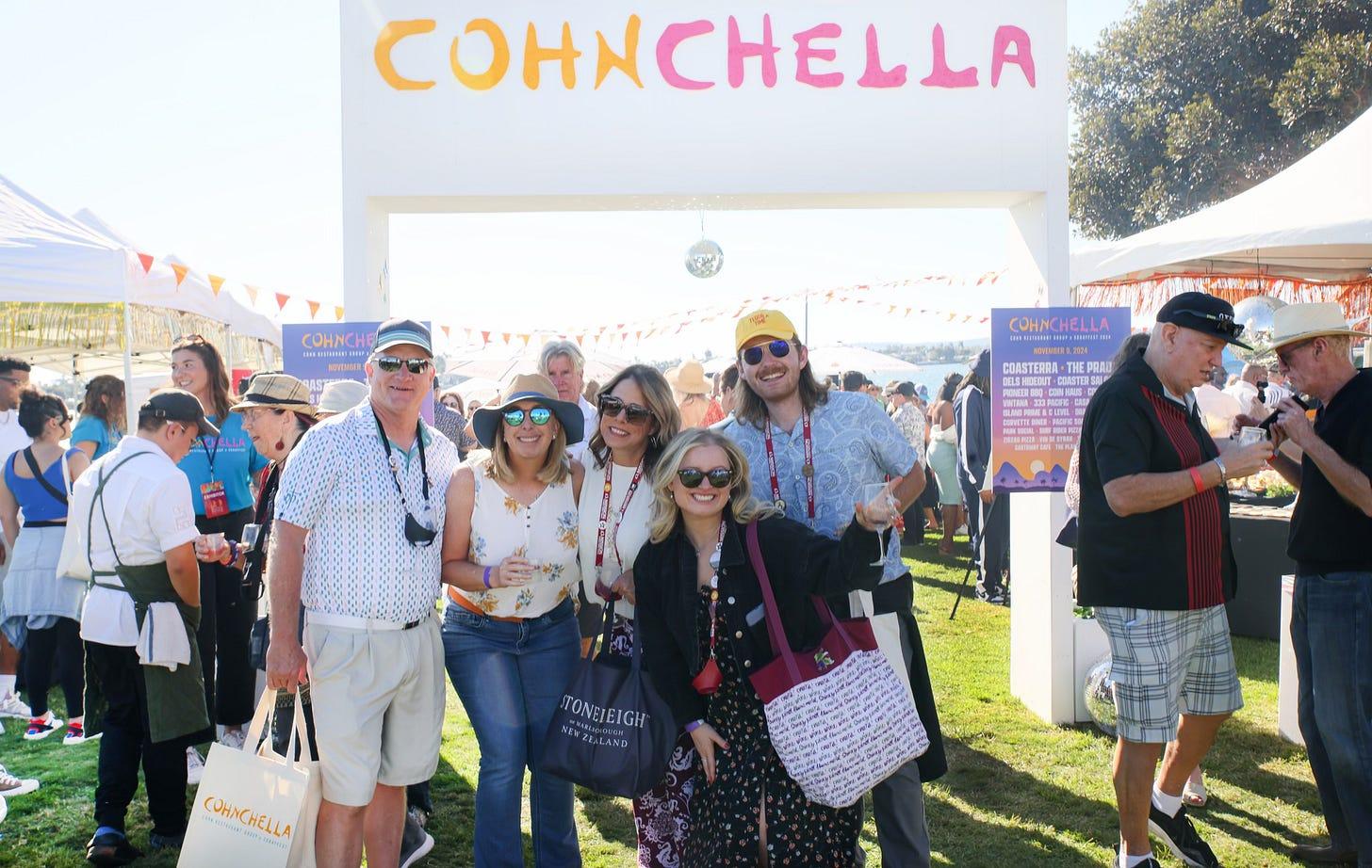 Festival guests standing beneath the CohnChella entrance at a waterfront food and wine event