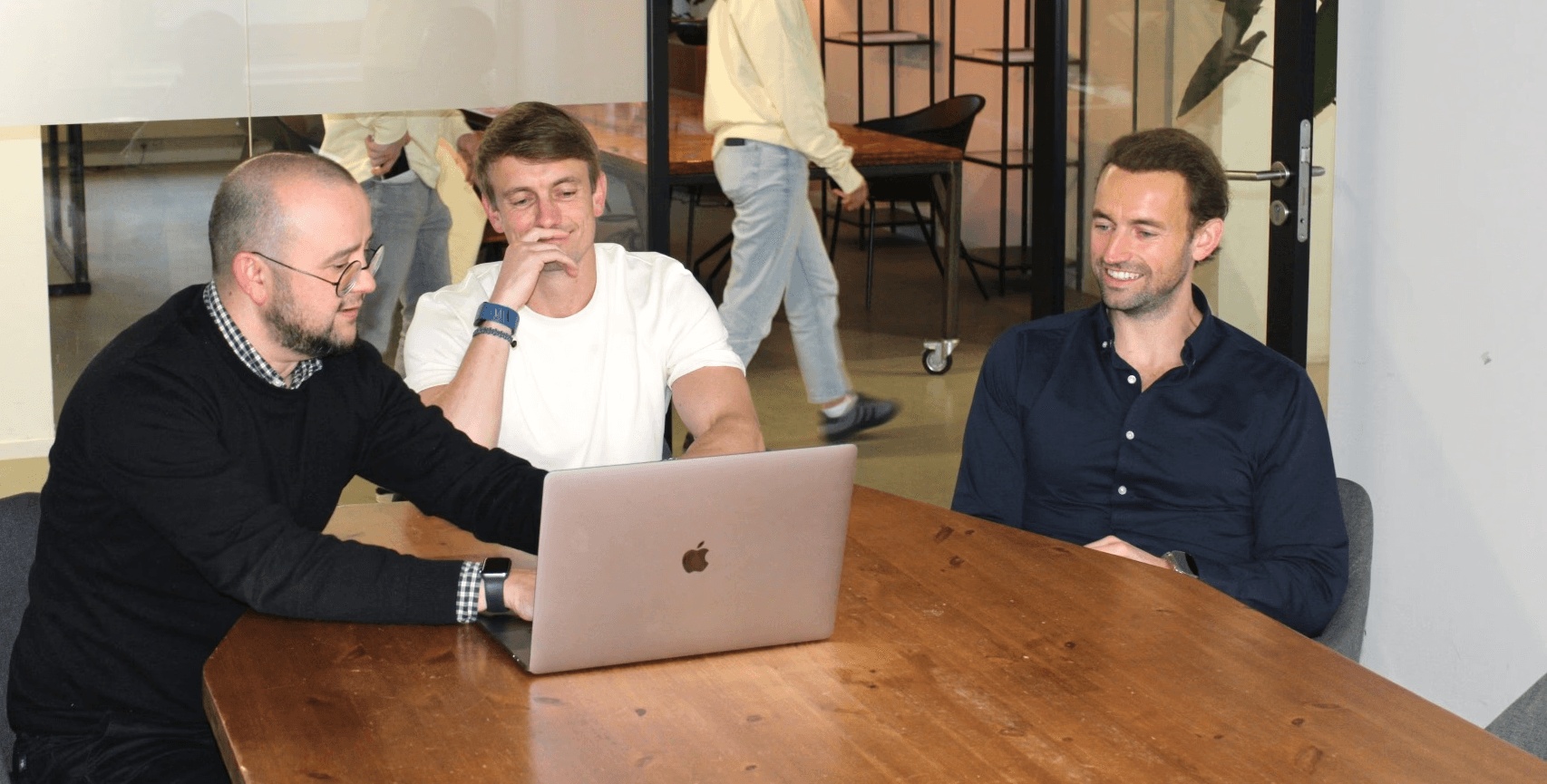 Churned’s founders gathered around a laptop, with Michiel Doornenbal seated on the right