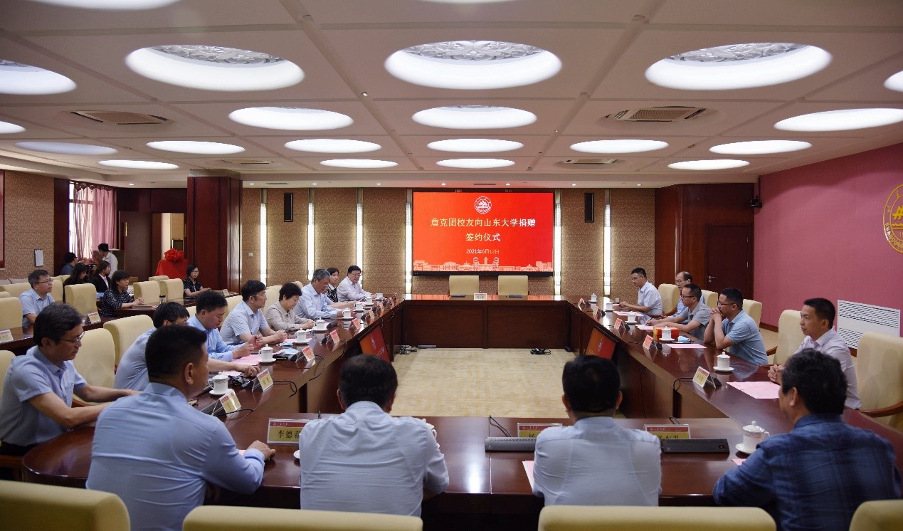 Micree Zhan and Shandong University representatives seated around a conference table during a 2021 donation ceremony