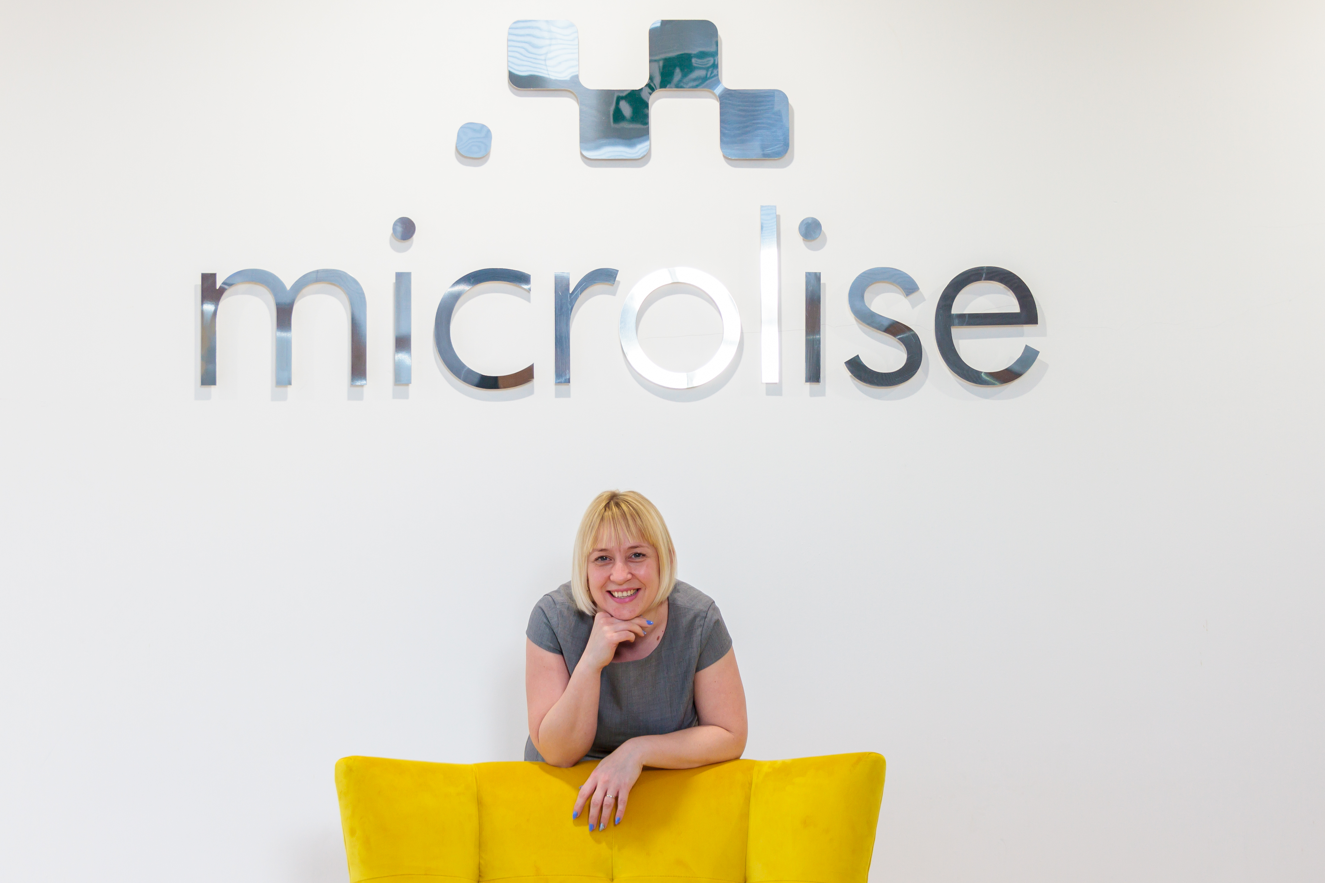 A Microlise employee pictured with bright yellow office seating
