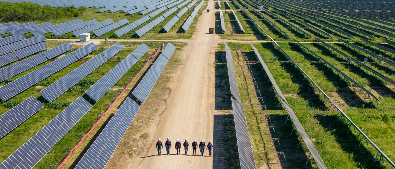 Workers walking between rows of solar panels
