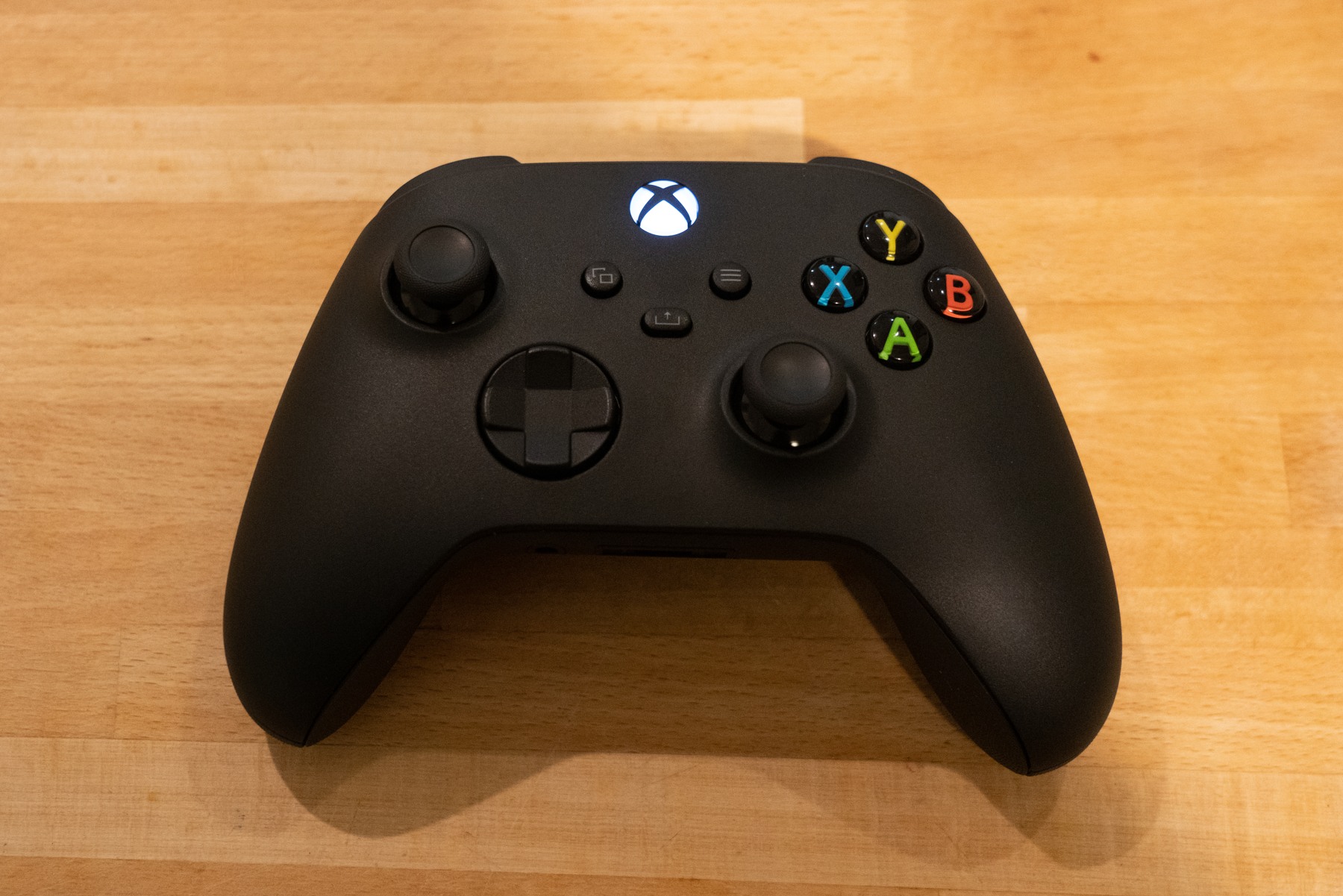 A black Xbox One controller on a wooden table