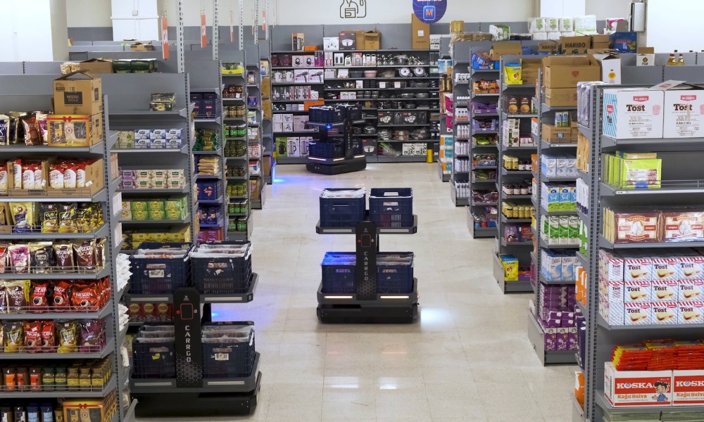 CarrGO mobile robots carrying grocery baskets between stocked shelves at the Bilkent operation