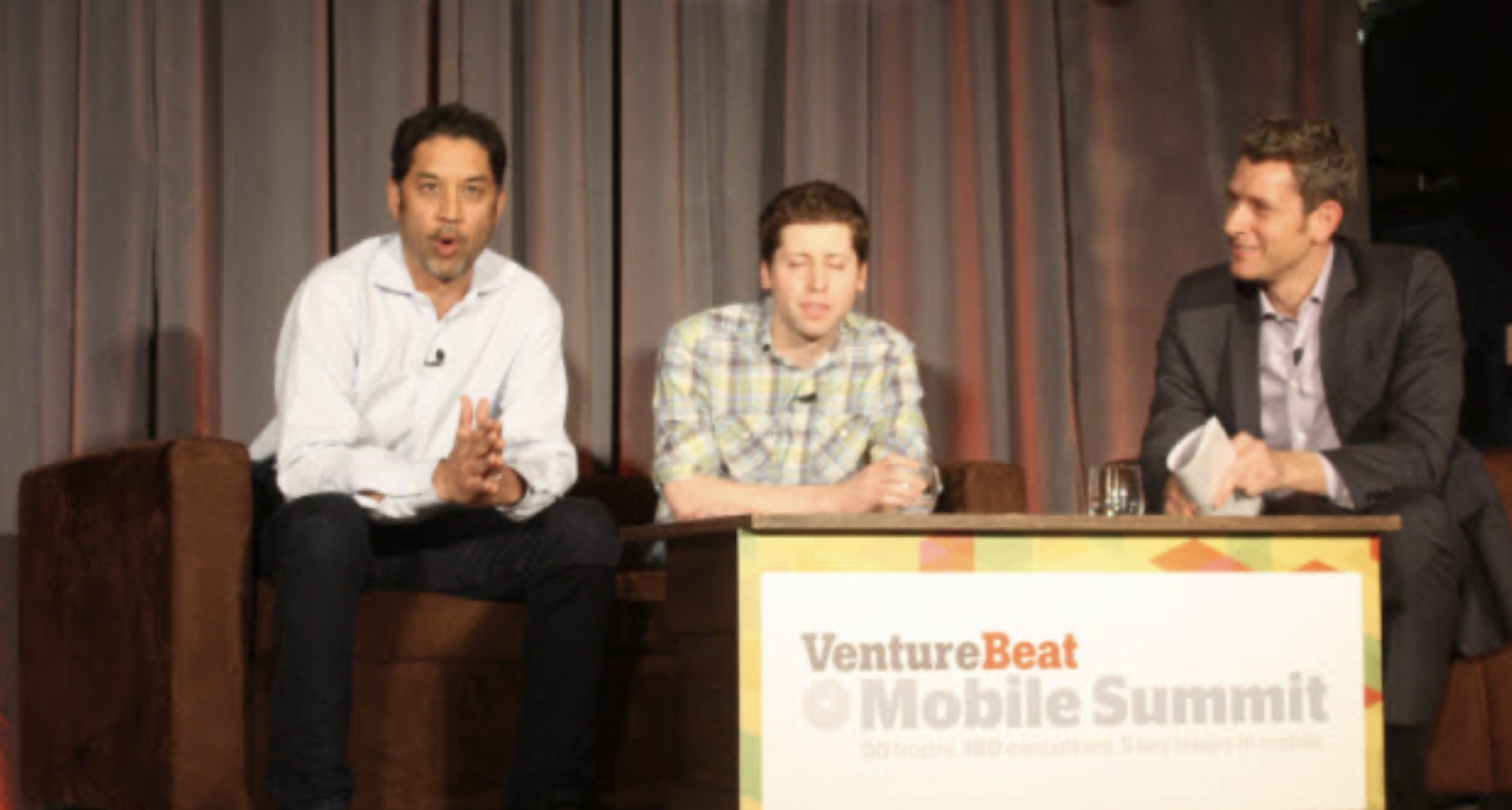 Mihir Shah seated on the left of a conference panel, with Sam Altman in the center at VentureBeat’s Mobile Summit.