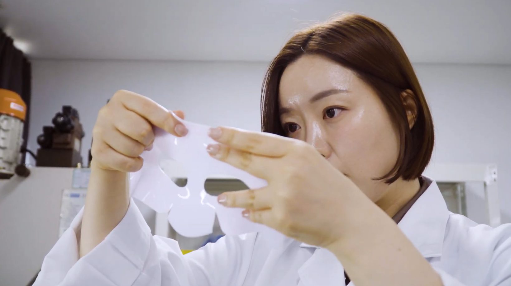 A Biodance researcher examining the shape of a hydrogel mask at a development bench