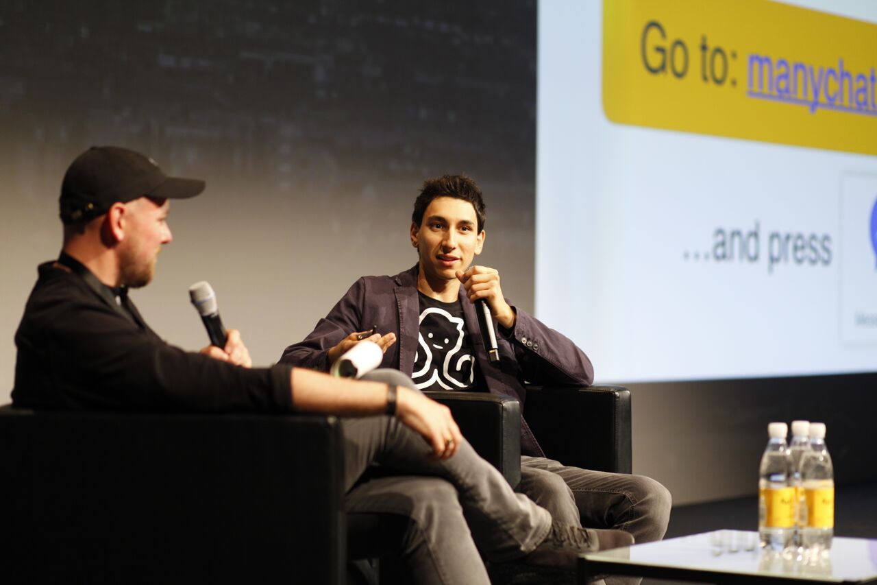 Mikael Yang, seated on the right, speaking into a microphone at Affiliate World Europe 2017