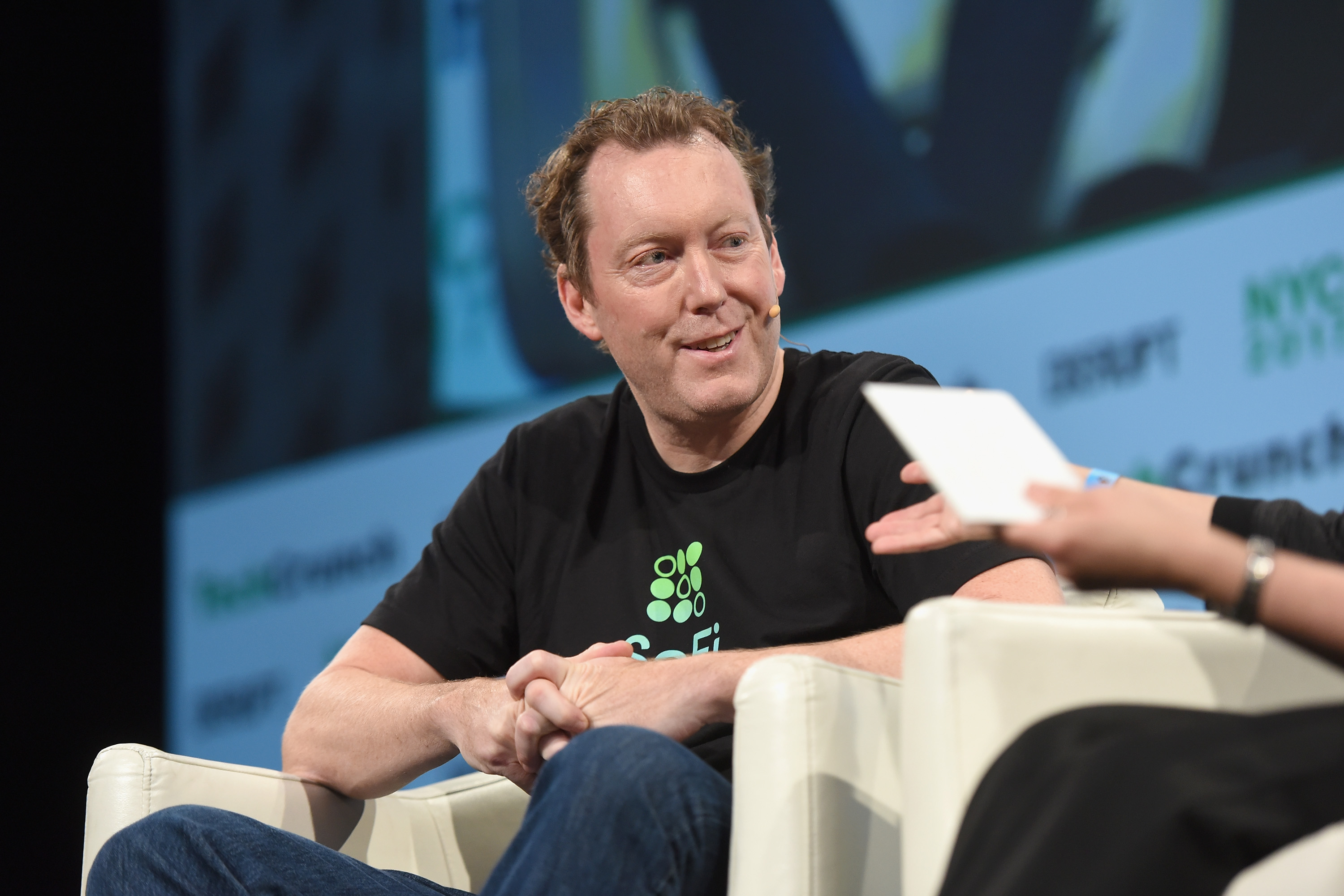 Mike Cagney in a SoFi T-shirt, seated onstage at TechCrunch Disrupt NY in 2017