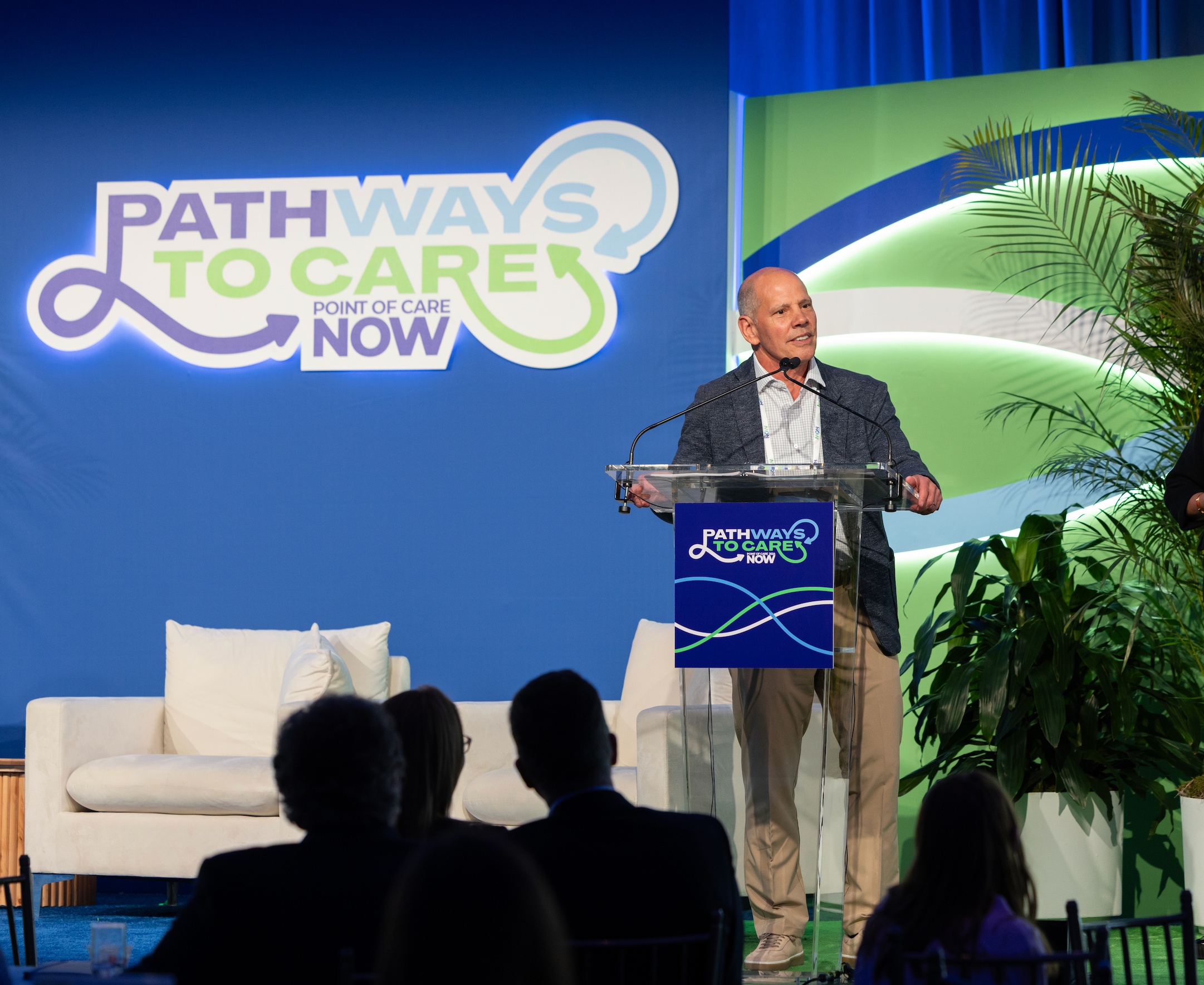 Mike Collette speaking at a lectern at the 2026 POC Now Summit in New York