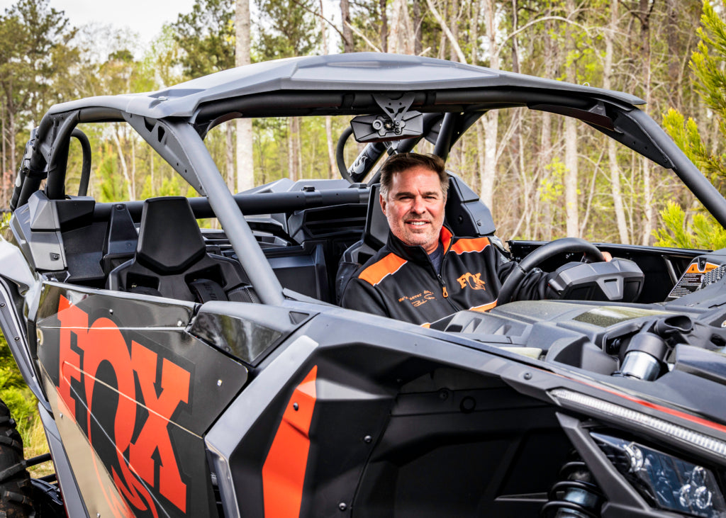 Mike Dennison at the wheel of a FOX-branded off-road side-by-side vehicle