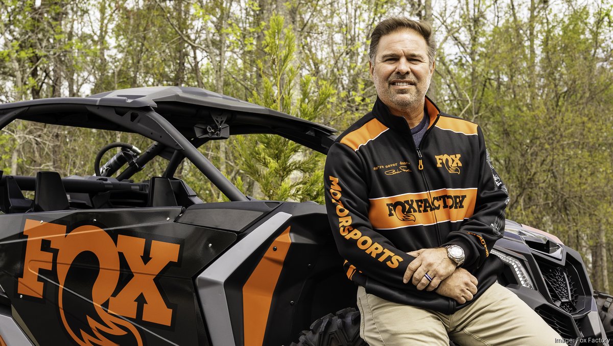 Mike Dennison beside a black and orange FOX off-road vehicle