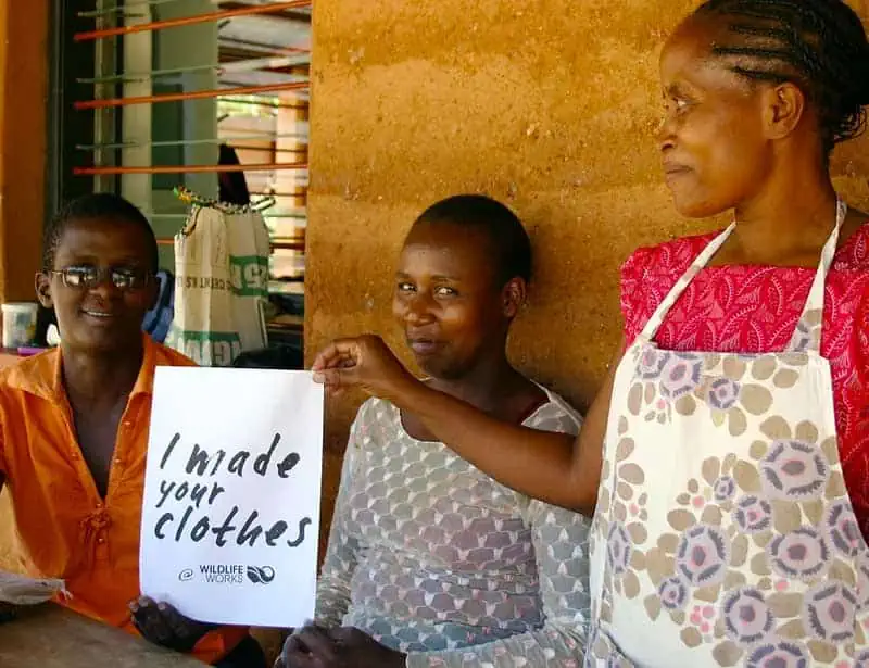 Wildlife Works garment makers holding a sign that reads I made your clothes