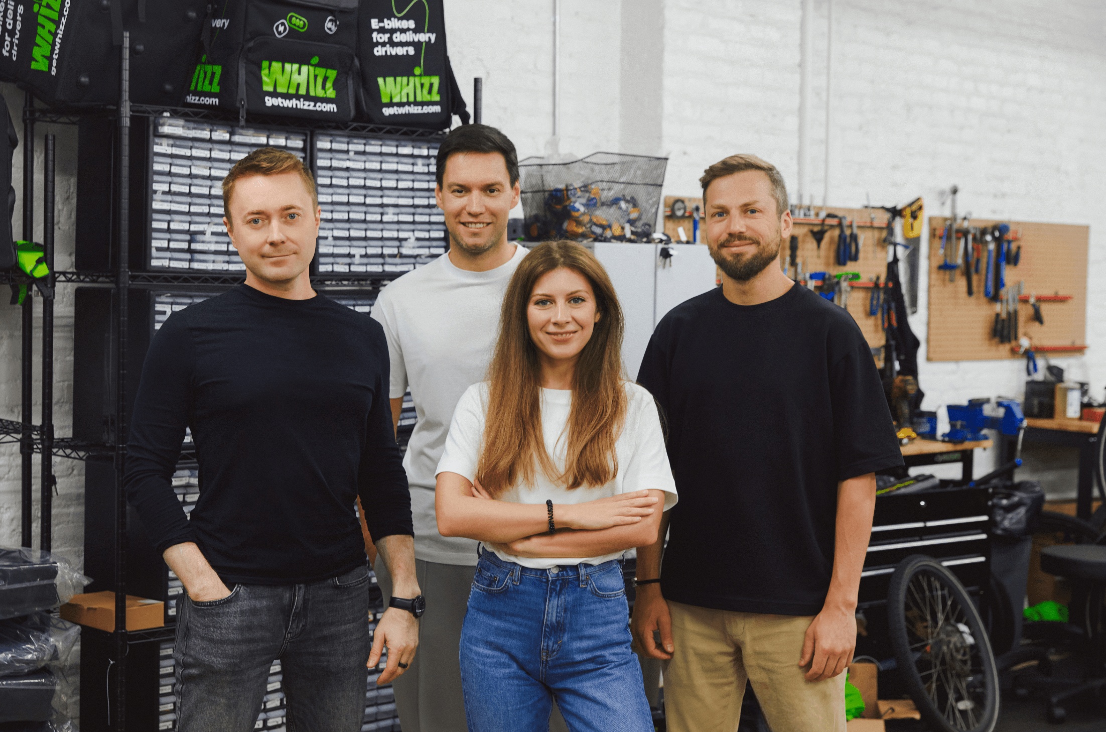 Whizz co-founders in a workshop, with delivery bags and tools behind them