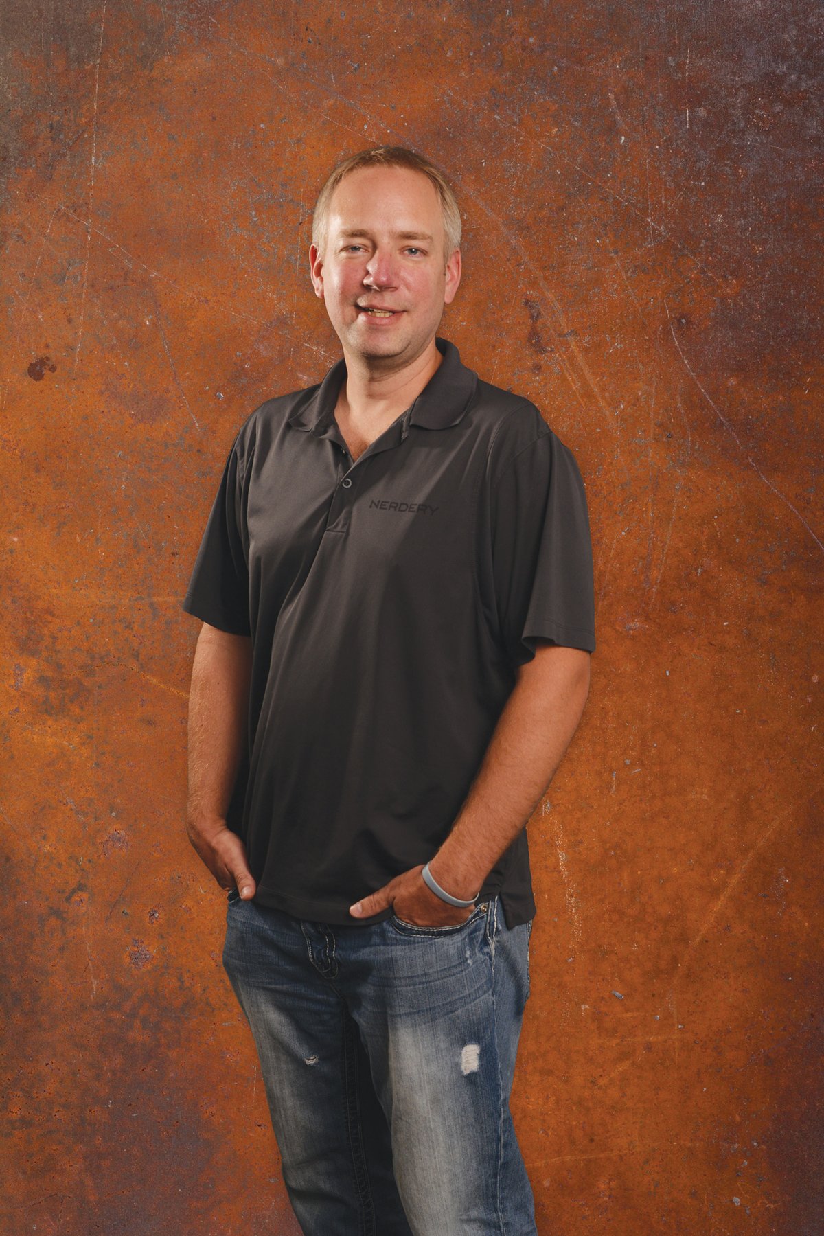 Archival press portrait of Mike Schmidt wearing a Nerdery polo shirt against an orange wall