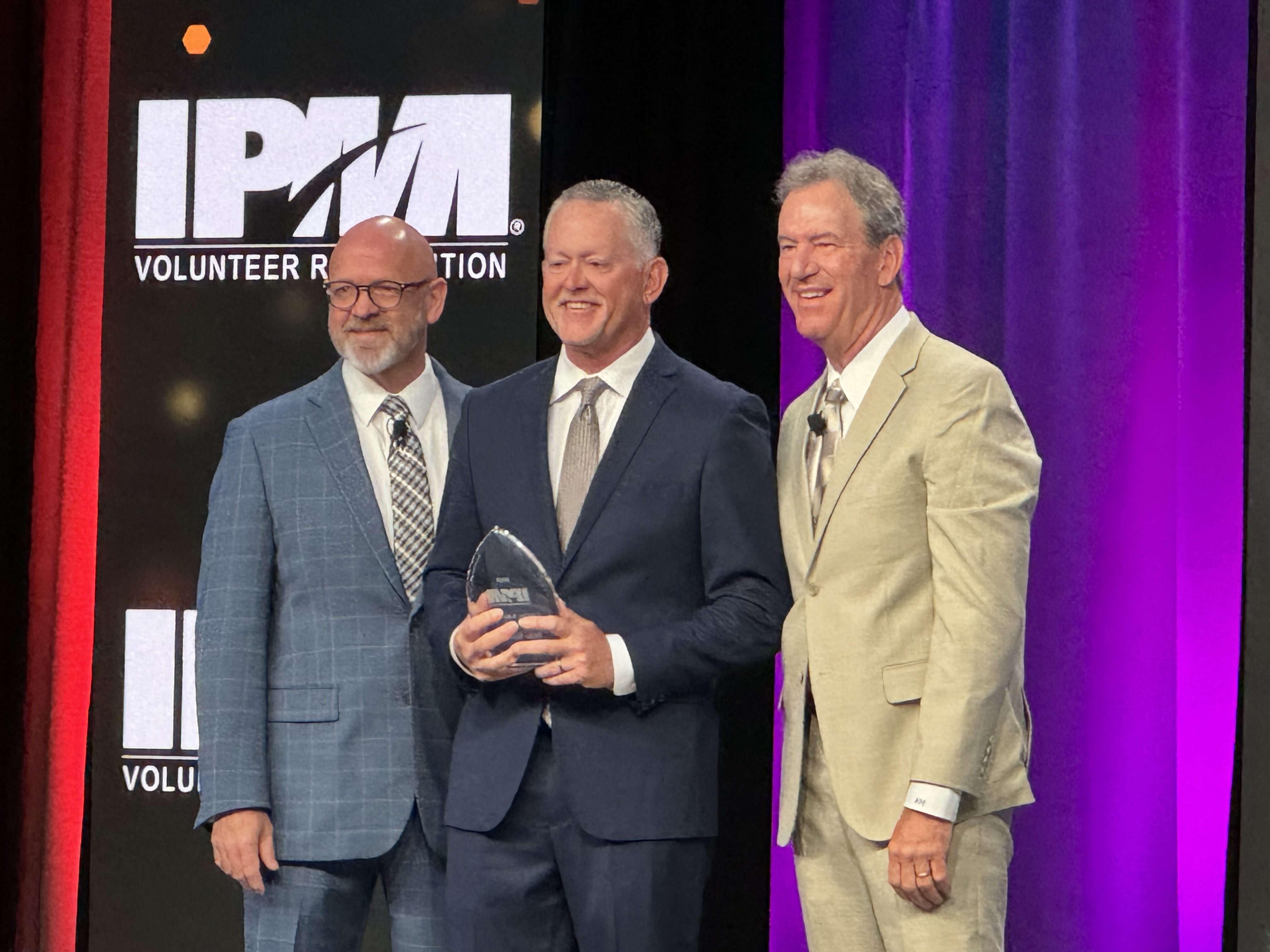 Mike Simmons, center, holding his award at the 2024 IPMI recognition ceremony