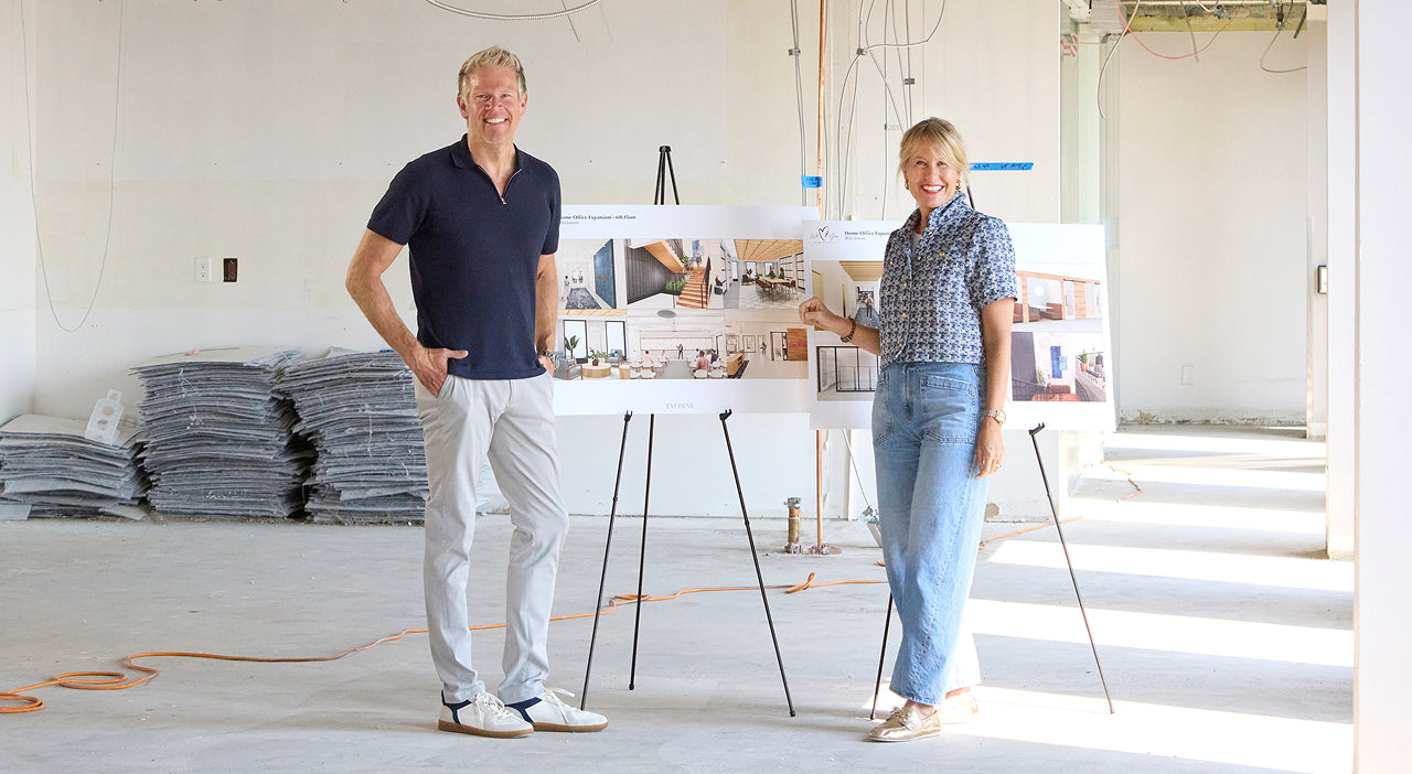 Mike and Megan Tamte standing beside office expansion plans in an unfinished space