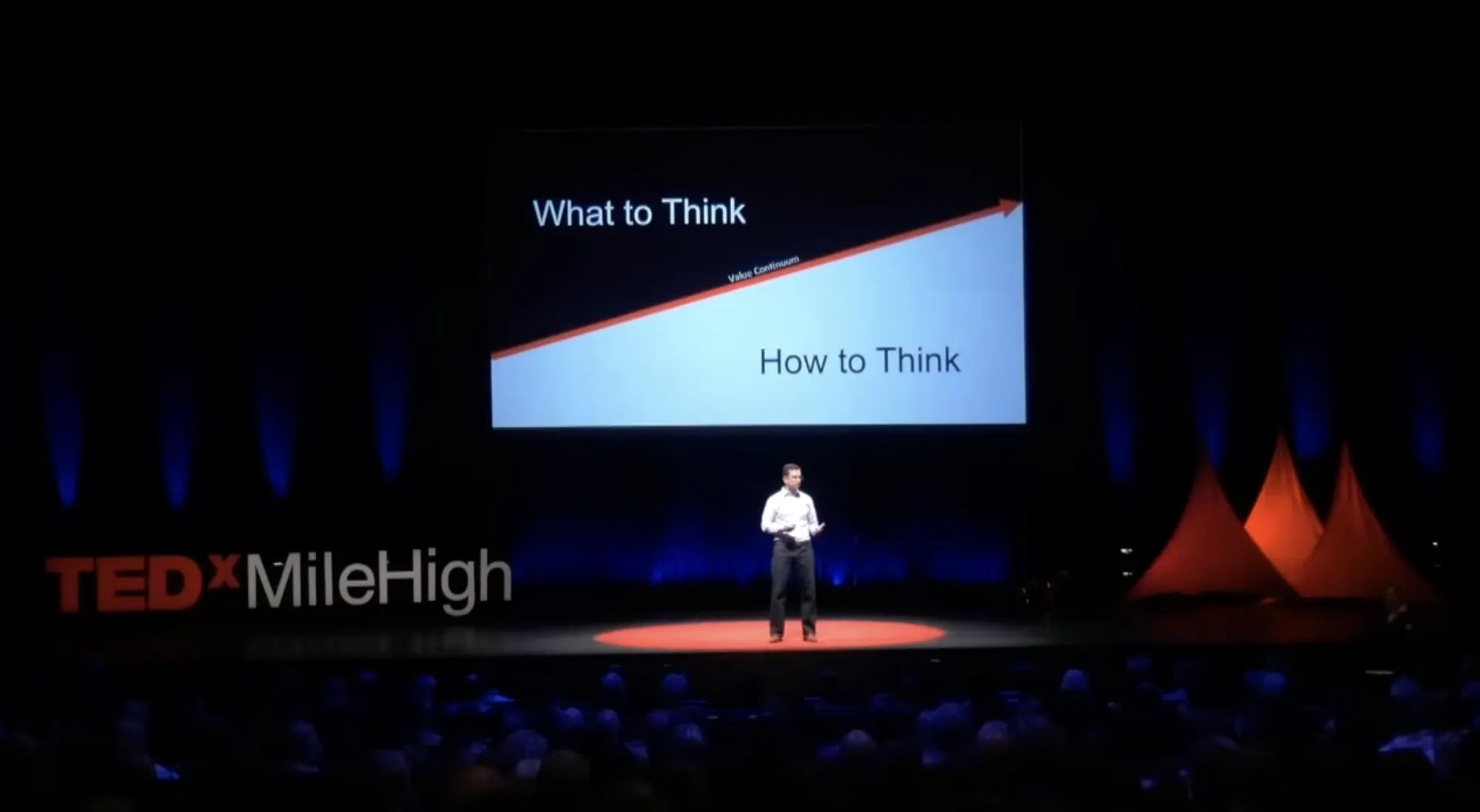 Mike Vaughan on the TEDxMileHigh stage beneath a diagram contrasting what to think and how to think