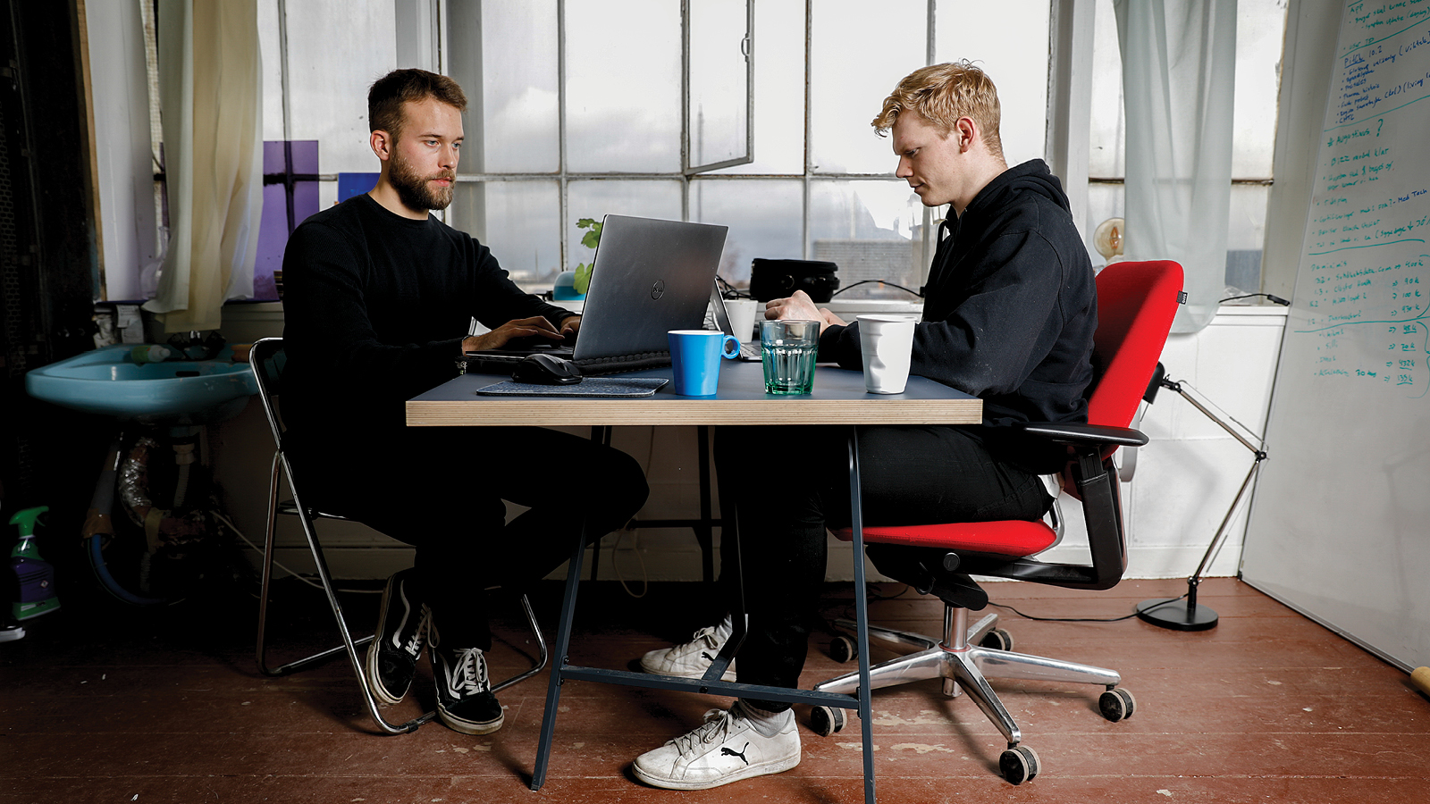 Teton co-founders working opposite each other at a table in their early shipyard office