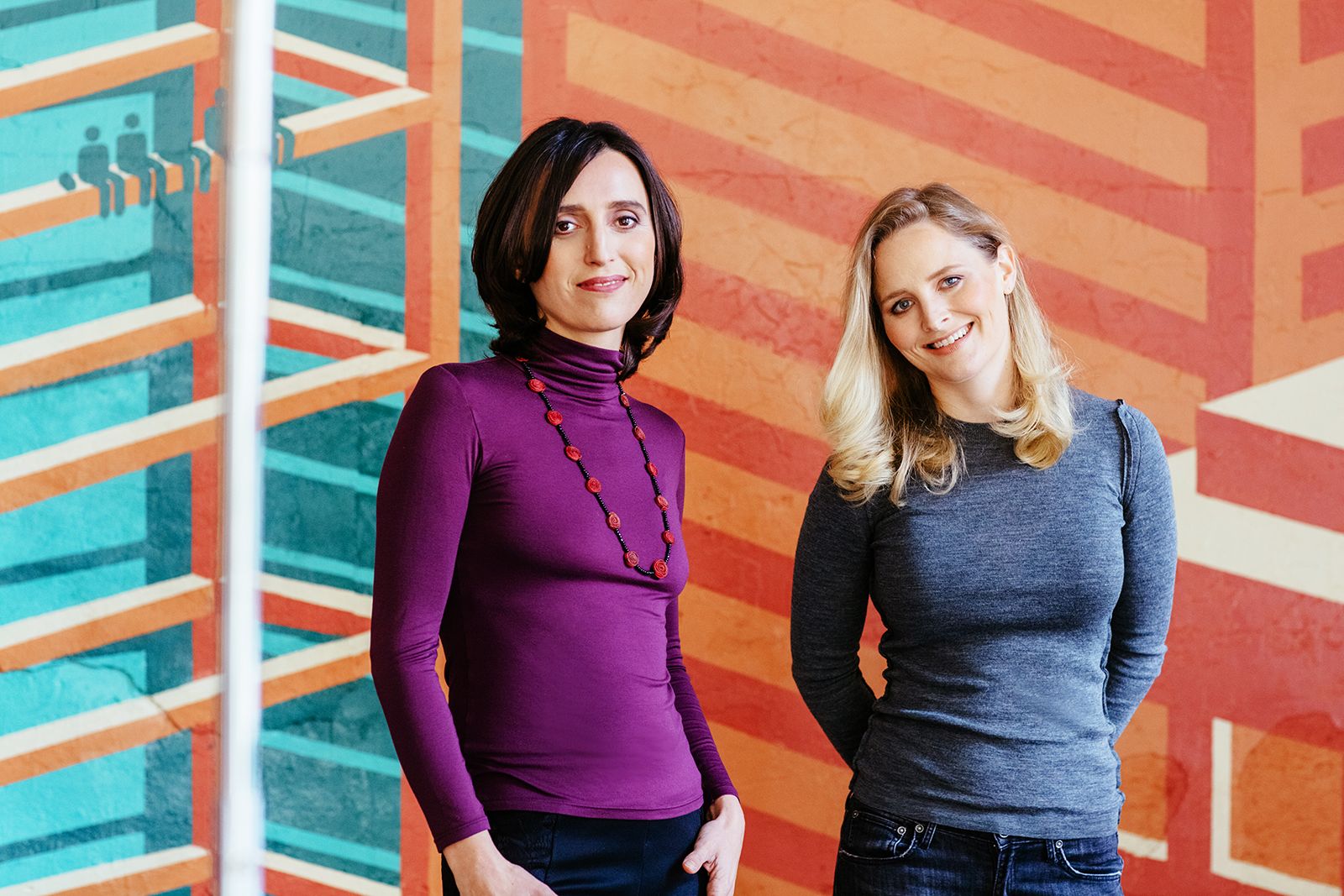 Milena Berry, left, and PowerToFly co-founder Katharine Zaleski standing together in front of a colorful mural