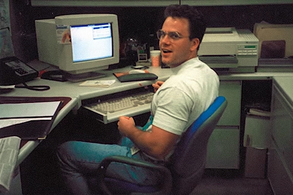 John Harms seated at an early desktop computer workstation