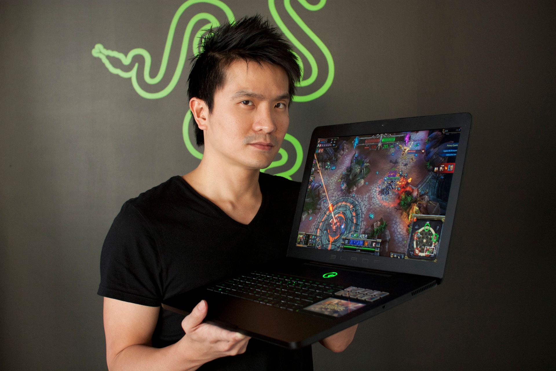 Min-Liang Tan holding the original Razer Blade gaming laptop, with its secondary touchscreen visible
