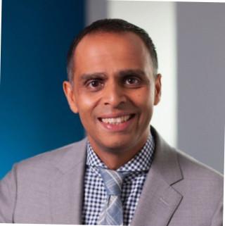 Minal Patel wearing a gray jacket and patterned shirt