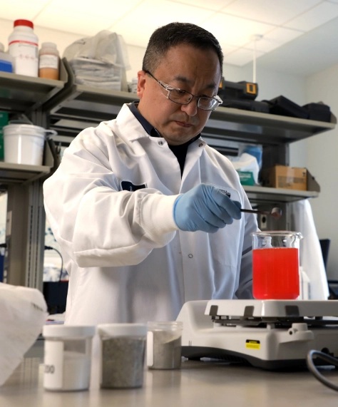 Scientist examining red liquid in a laboratory, in a photograph published by MTI