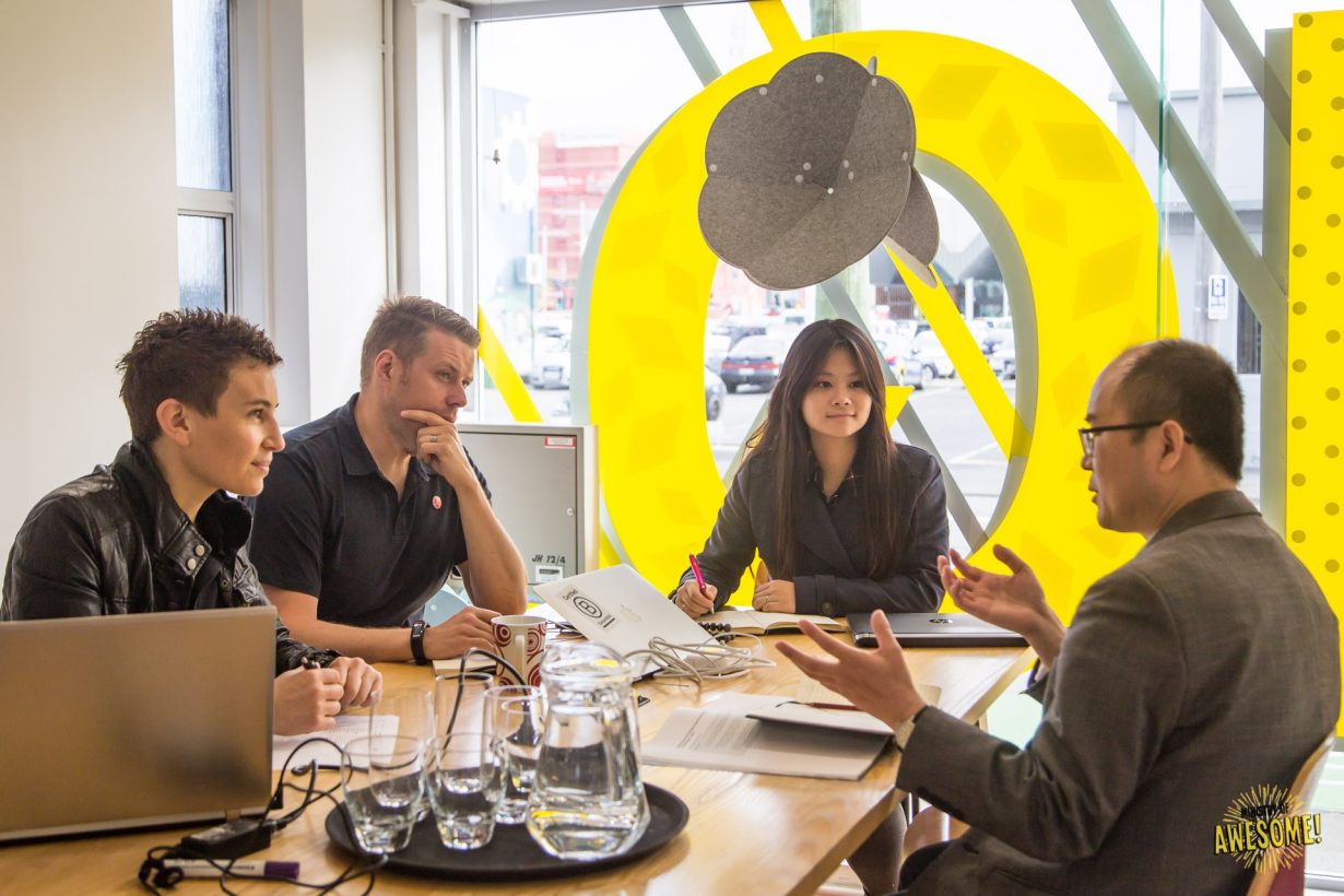 Four people discussing ideas around a table in Ministry of Awesome’s workspace